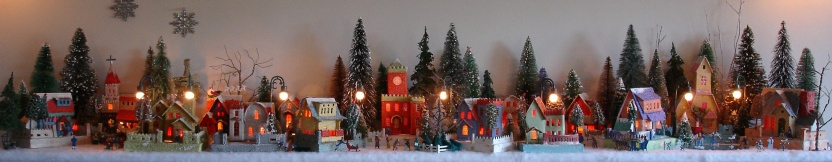 Antique Christmas cardboard house putz (village) on fireplace mantel at night (50K)