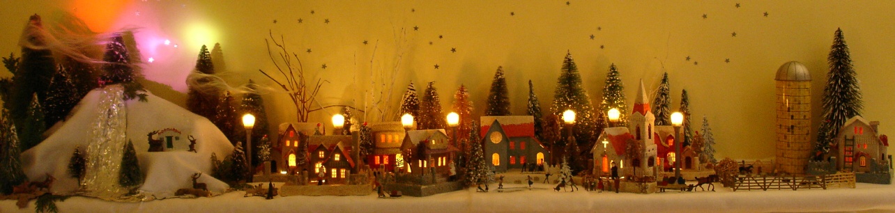 Antique Christmas cardboard house putz (village) on fireplace mantel at night (70K)
