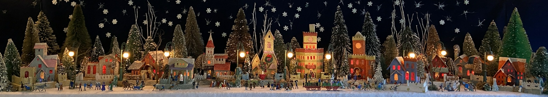 Antique Christmas cardboard house putz (village) on fireplace mantel at night (280K)