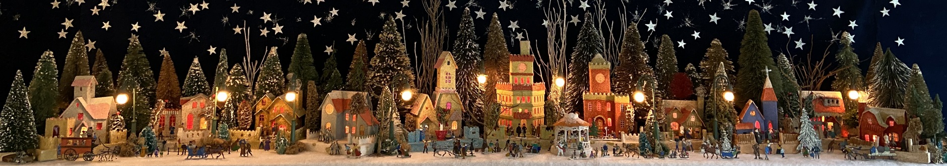 Antique Christmas cardboard house putz (village) on fireplace mantel at night (280K)